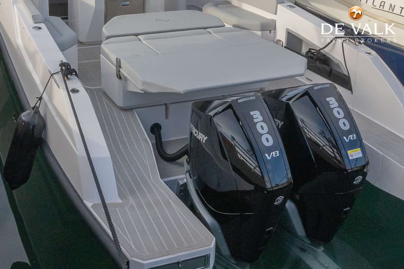Twee zwarte Mercury 300 V8 buitenboordmotoren zijn zichtbaar aan de achterkant van een boot met grijze kussens en een…