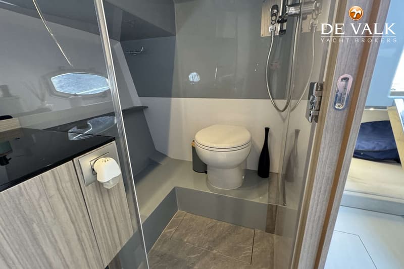 Een badkamer op een boot met een toilet, douche, wastafel en een patrijspoort. — Rio Yachts Daytona 35