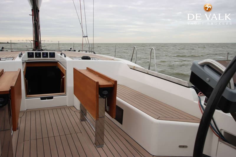 Een dek van een zeilboot met houten vloer, een open kajuitingang en een opklapbare houten tafel. — Arcona 50
