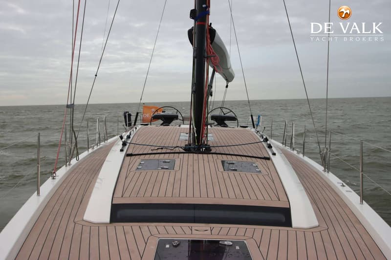 Een bovenaanzicht van het dek van een zeilboot met een houten dek, mast en twee stuurwielen, varend op zee. — Arcona 50