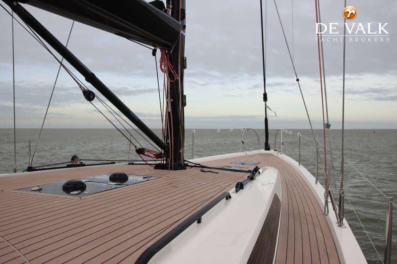 Een zeilboot met een houten dek en een zwarte mast vaart op open water onder een bewolkte hemel. — Arcona 50
