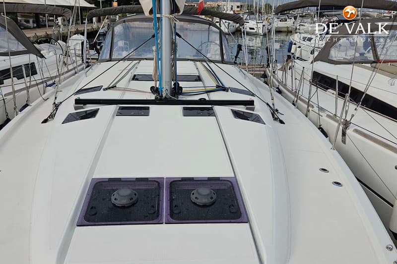 Een witte zeilboot ligt in een haven, met een mast, lijnen, luiken en een buiskap zichtbaar. — Jeanneau Sun Odyssey 490