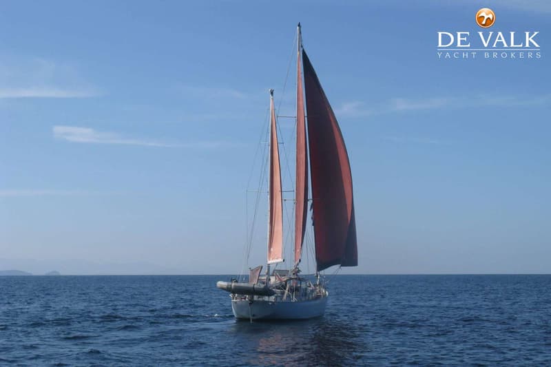 Een zeilboot met twee masten en rode zeilen vaart op open water onder een helderblauwe lucht. — Frans Maas Calypso 43