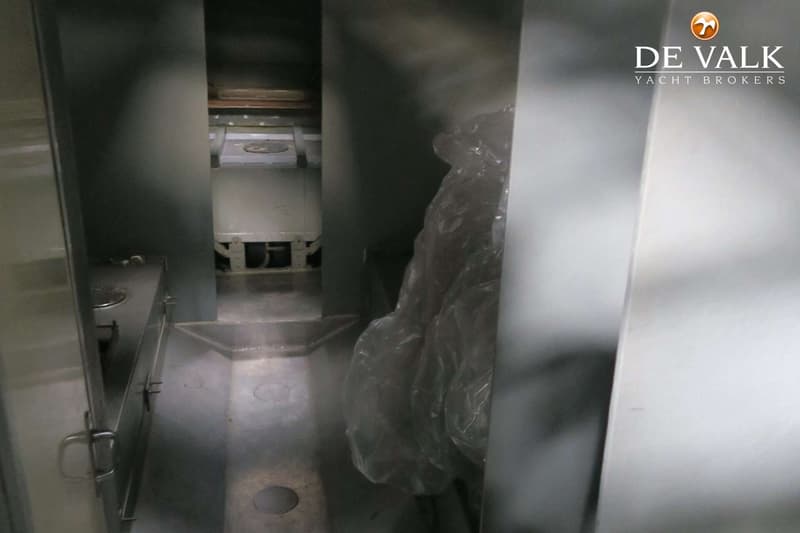 Een smalle doorgang met een metalen aanrechtblad en een kookplaat aan de linkerkant, en een grote plastic zak aan de…