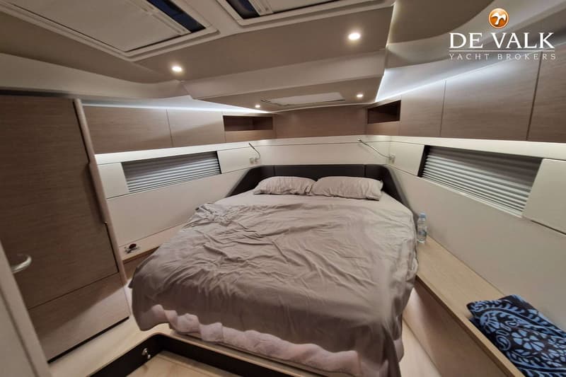 Een slaapkamer in een boot met een tweepersoonsbed, twee kussens en een grijs dekbed. — Hanse 460