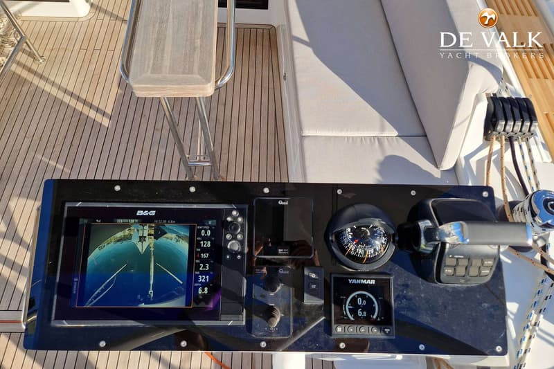 Een detailfoto van het dashboard van een boot met diverse navigatie-instrumenten, een kompas en een motorbediening.