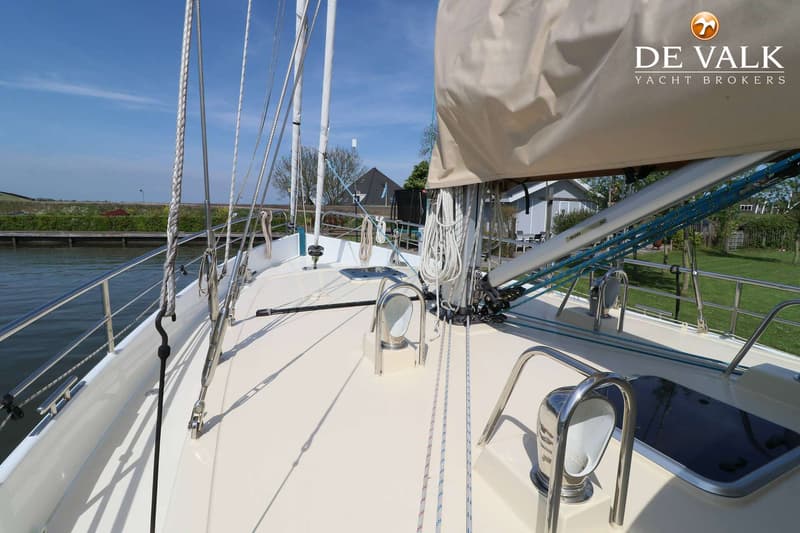 Een bovenaanzicht van het dek van een zeilboot met een opgerold zeil, touwen, lieren en een reling. — Noordkaper 48 -S