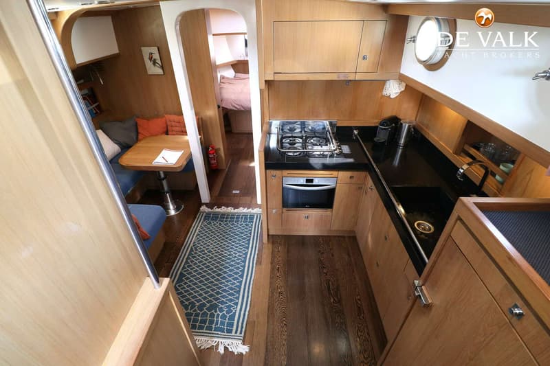 Een interieur van een boot met een kombuis, eethoek en een doorgang naar een slaapcabine. — Noordkaper 48 -S