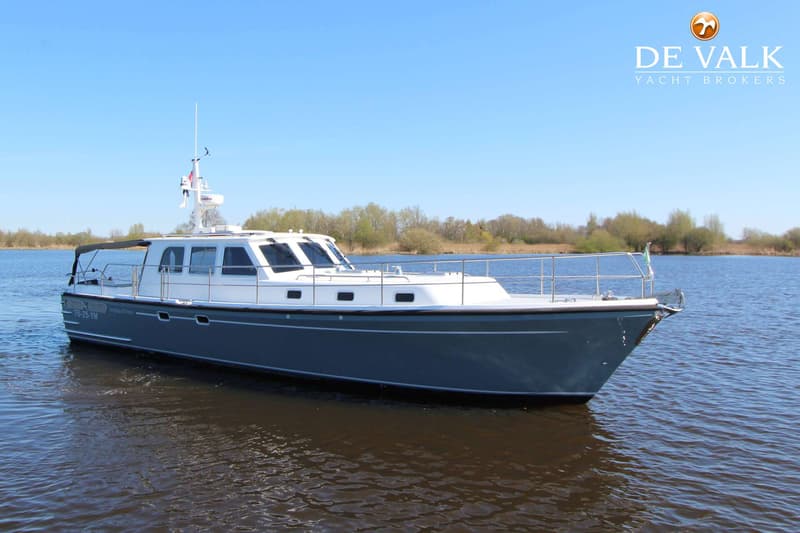 Een blauw-witte motorboot met een grijze romp en een witte opbouw ligt in het water onder een heldere blauwe lucht.
