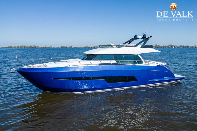 Een blauw-witte motorjacht vaart op open water onder een helderblauwe lucht.