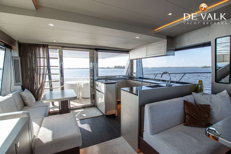 De foto toont het interieur van een boot met een zithoek, een kombuis en uitzicht op water. — Van der Heijden Phantom 70