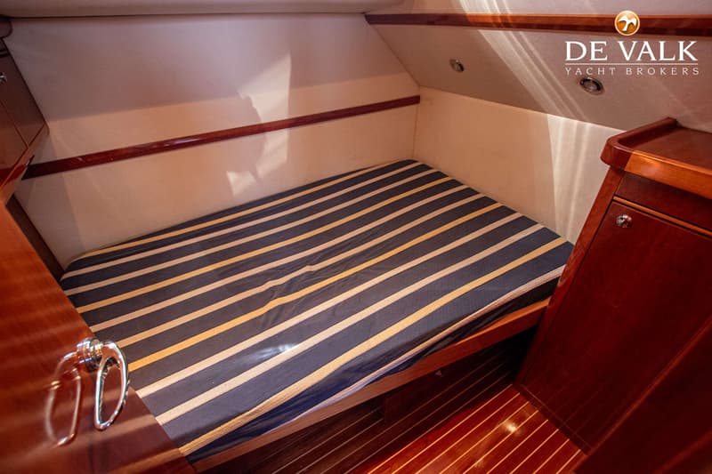 De foto toont een kajuit met een gestreept matras, houten vloer en houten kasten. — Apreamare 12