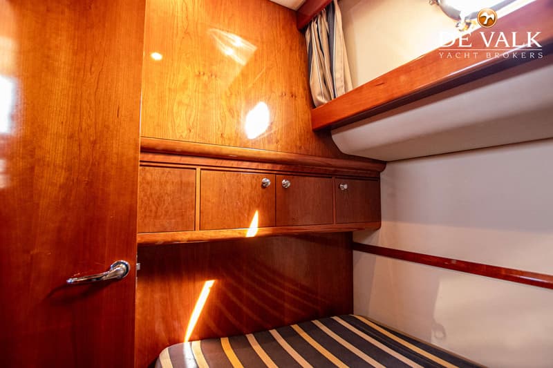 Een kajuit met houten wanden, een bed met gestreepte bekleding, kasten en een gordijn. — Apreamare 12