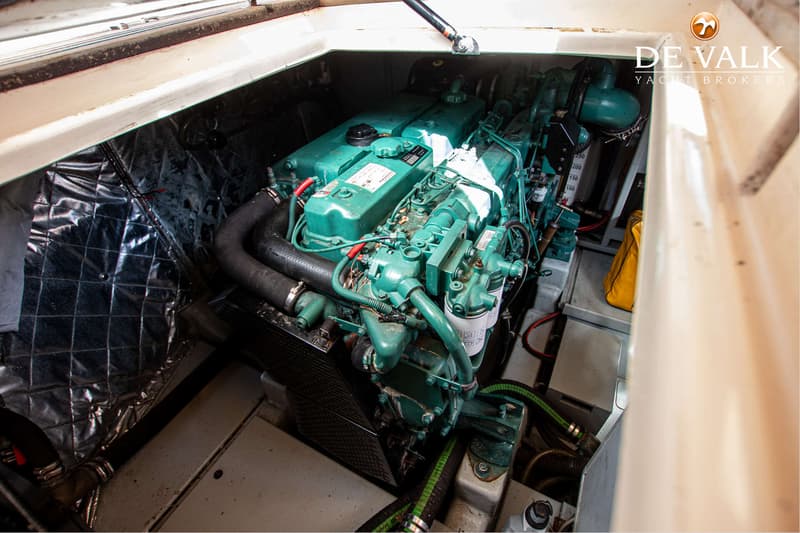Een groene motor met slangen en bedrading is zichtbaar in een motorruimte met geluidsisolatie.