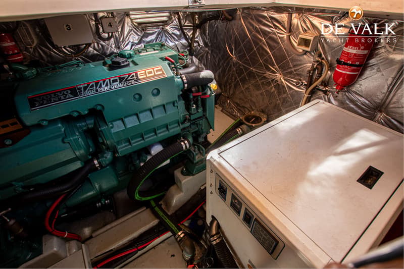 Een Volvo Penta TAMD74EDC motor en een wit apparaat met bedieningspaneel zijn zichtbaar in een motorruimte.