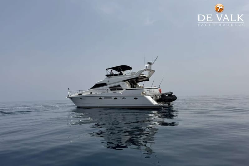 Een witte motorboot met de naam "Ocean Drive" vaart op kalm water onder een lichtgrijze lucht. — Johnson 56