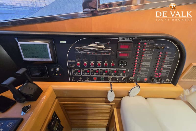 Een navigatiepaneel met diverse schakelaars, meters en een scherm is zichtbaar in een bootinterieur.