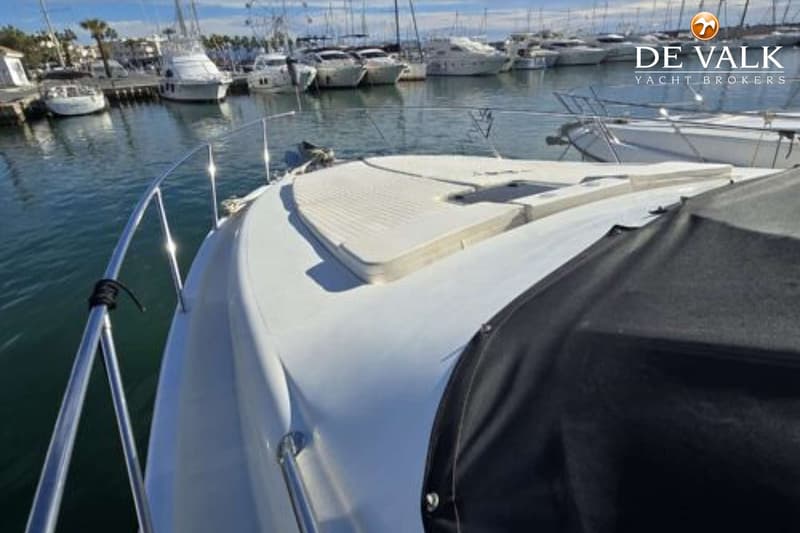 Een witte boot met een zwart afdekzeil en een wit dek, liggend in een haven met andere boten. — Johnson 56