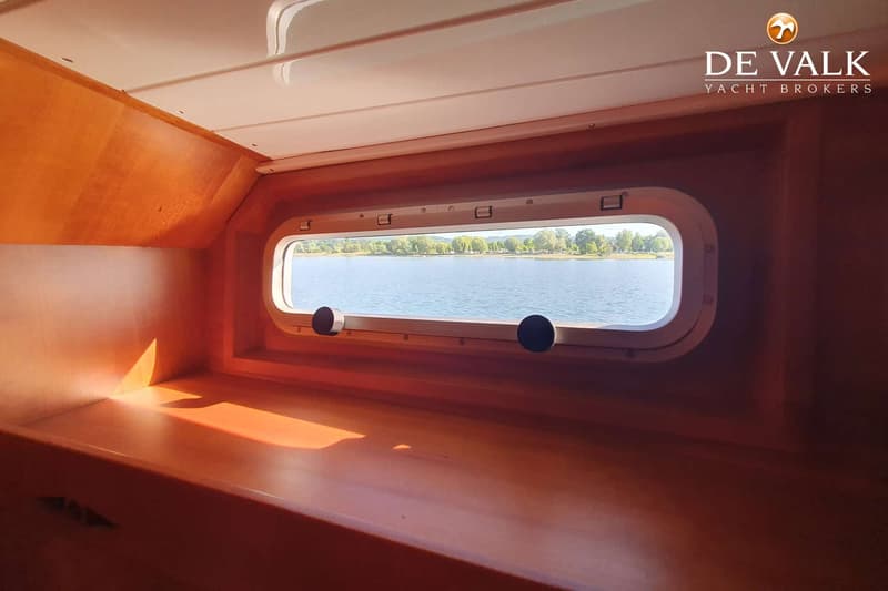 Een interieur van een boot met een langwerpig raam dat uitkijkt op water en een beboste oever. — Martin 44 Trawler