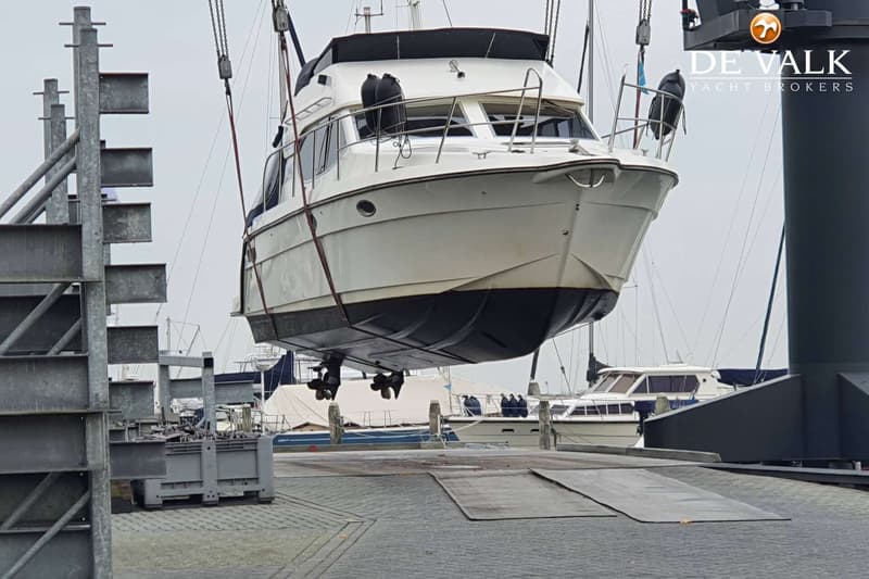 Een witte motorboot met een donkere romp wordt uit het water getild door een kraan. — Galeon 380 Fly