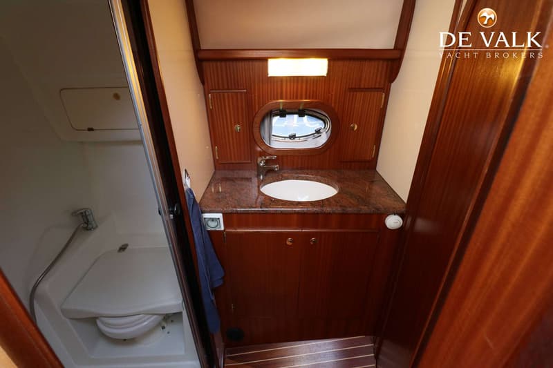 De foto toont een badkamer met een toilet, wastafel en een patrijspoort.