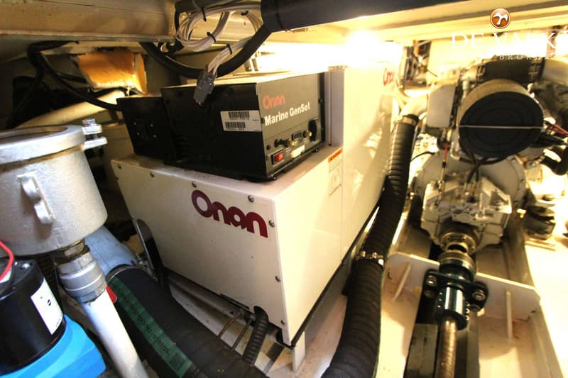 Een witte Onan Marine GenSet is zichtbaar, omringd door diverse slangen, kabels en andere motoronderdelen.