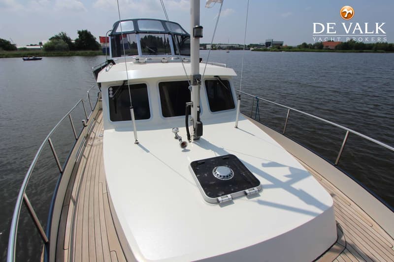 Een witte boot met een houten dek en een stuurhut met donkere ramen, liggend aan een waterweg. — Boarncruiser 35 Classic Line