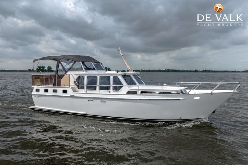 Een witte motorboot met een donkere kap vaart op water onder een bewolkte lucht. — Almkruiser 12.65