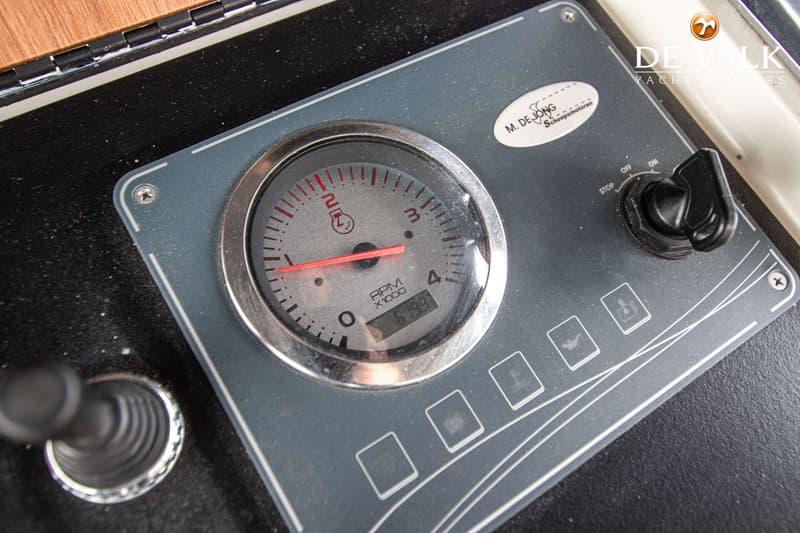 Een detailfoto van een dashboard met een toerenteller, een contactslot en vier knoppen met symbolen.