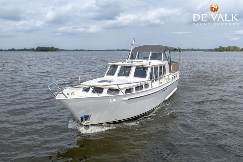 Een witte motorboot met een zwarte kap vaart op een meer onder een bewolkte hemel. — Almkruiser 12.65