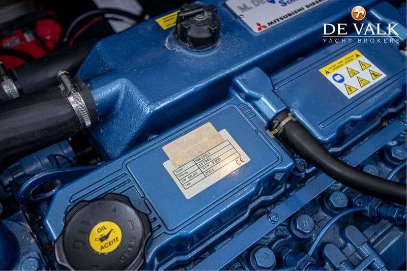 Een close-up van een blauwe scheepsmotor met een typeplaatje, oliedop en waarschuwingsstickers.