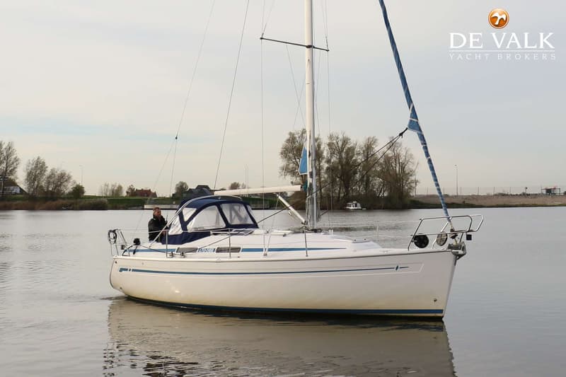 Een witte zeilboot met blauwe strepen en een blauwe buiskap vaart op rustig water, met een persoon aan boord. — Bavaria 31