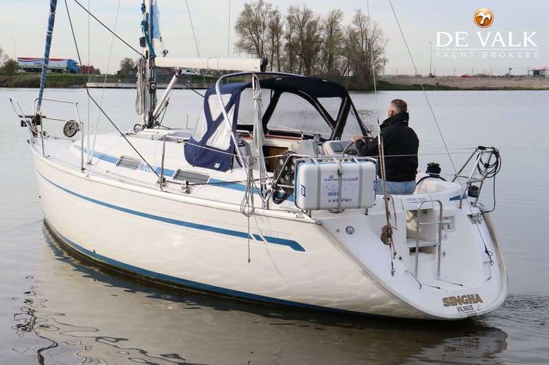 Een witte zeilboot met blauwe strepen en een blauwe buiskap vaart op rustig water, met een persoon aan het roer. — Bavaria 31