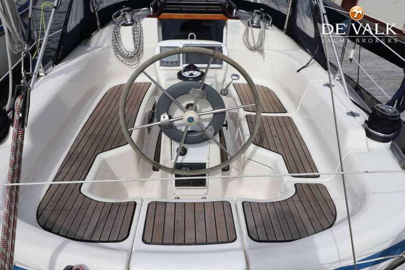 Een stuurwiel met kompas en navigatie-instrumenten in de kuip van een zeilboot met teakhouten dek. — Bavaria 31