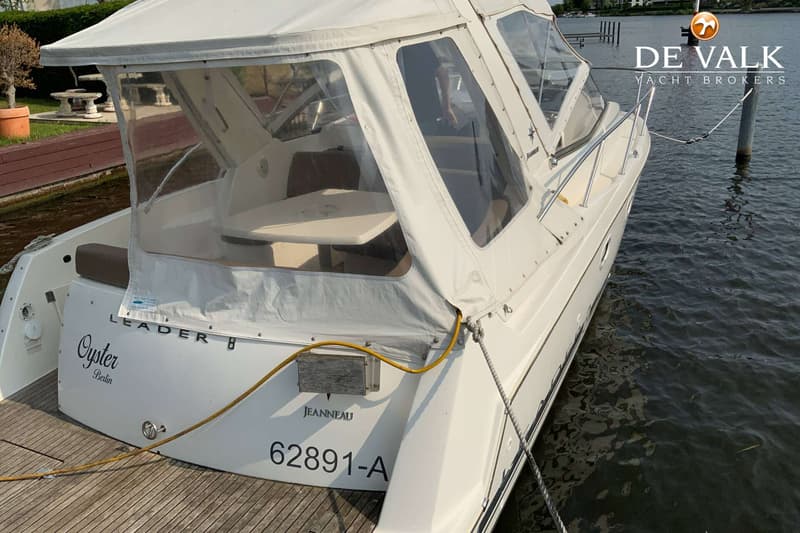 Een witte Jeanneau Leader 8 boot met de naam "Oyster Berlin" en registratienummer 62891-A, ligt aangemeerd aan een houten…