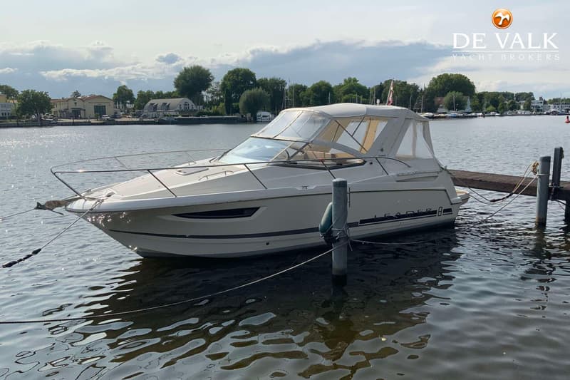 Een witte motorboot met de naam "LEADER" ligt afgemeerd aan een houten steiger. — Jeanneau Leader 8