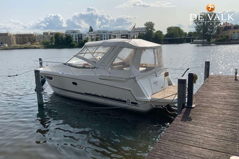 Een witte boot met de tekst "LEADER" op de zijkant ligt aangemeerd aan een houten steiger. — Jeanneau Leader 8