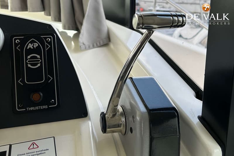 Een close-up van een bedieningspaneel met knoppen voor thrusters en een chromen hendel.