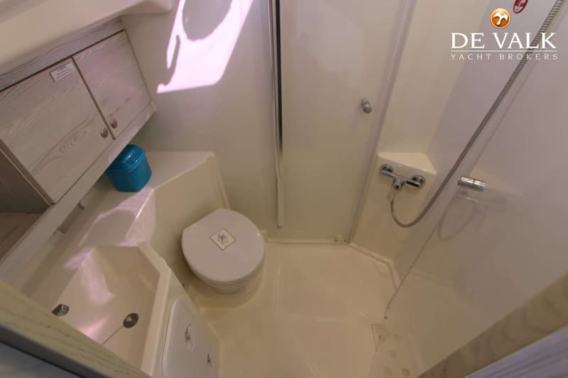 Een compacte badkamer met een toilet, wastafel en douche in een lichte kleurstelling.