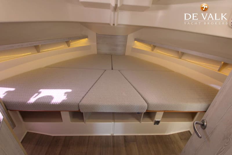 De foto toont een kajuit met een V-vormig bed, opbergruimte onder het bed en sfeerverlichting langs de zijkanten.