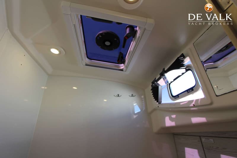 De foto toont een interieur met een dakluik, een patrijspoort met zonwering, twee kledinghaken en inbouwverlichting.
