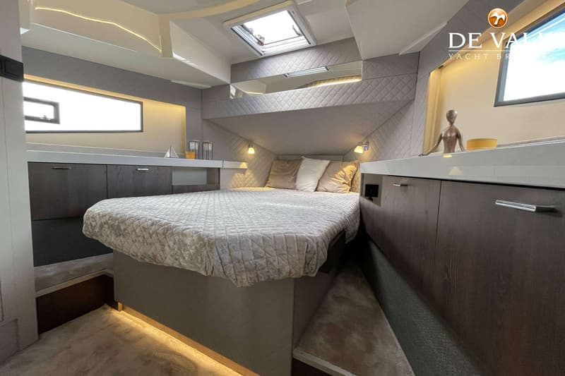 Een slaapkamer in een boot met een groot bed, kussens, een dekbed, en kasten aan weerszijden. — Cobra Yachts Maestro 42