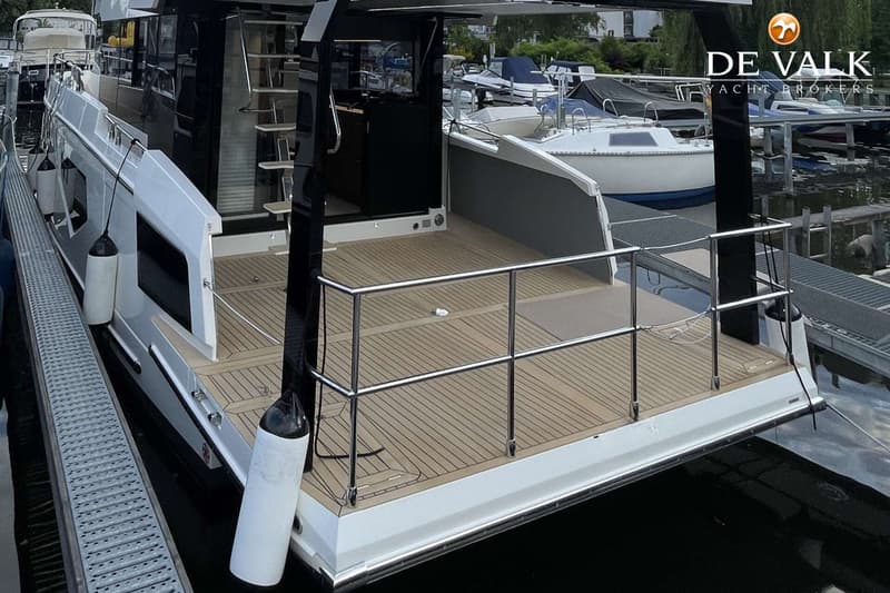 Een witte boot met een houten dek en een zilveren reling ligt aangemeerd aan een steiger. — Cobra Yachts Maestro 42