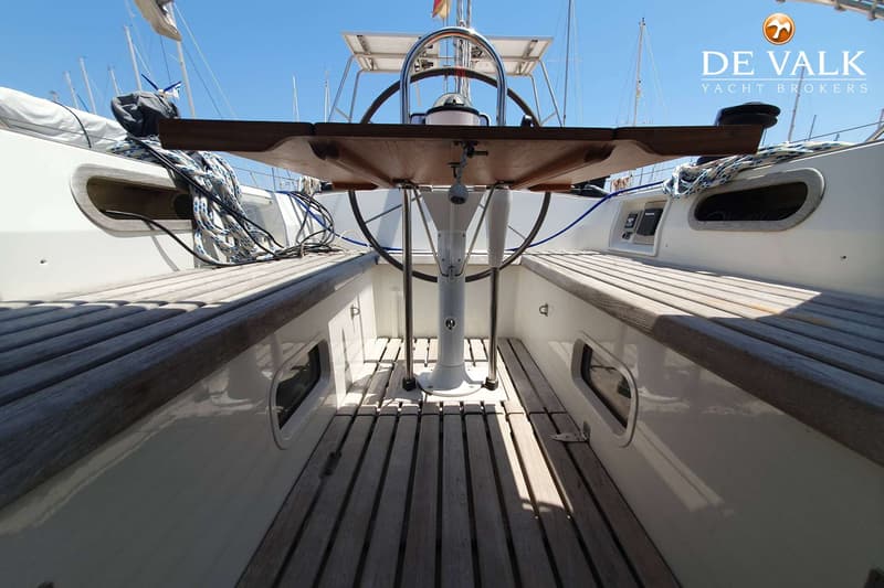 Een houten dek en een stuurwiel met een tafel in het midden van een boot. — Contest 43/44