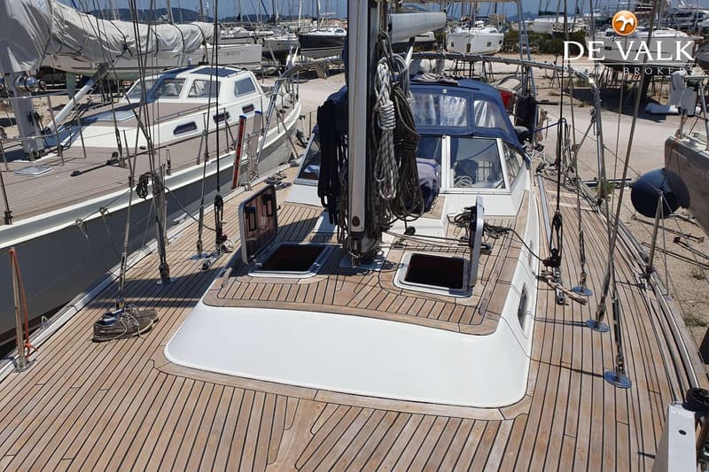 Een bovenaanzicht van het dek van een zeilboot met een houten dek, twee open luiken en een mast met touwen. — Contest 43/44