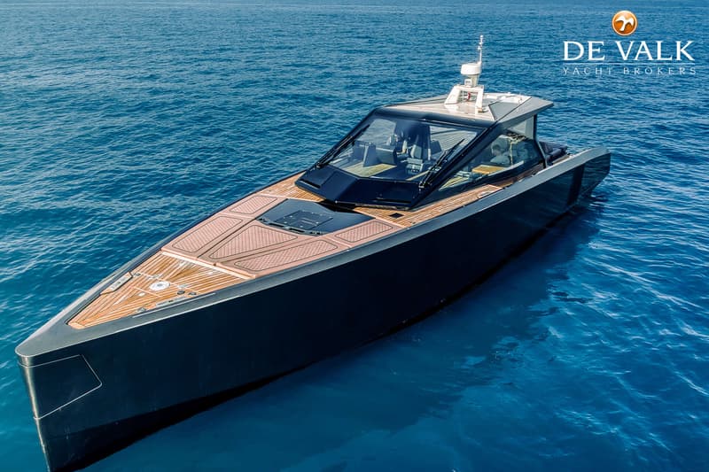 Een donkergrijze motorboot met een houten dek en een glazen kajuit ligt op helderblauw water. — Wally WallyPower58