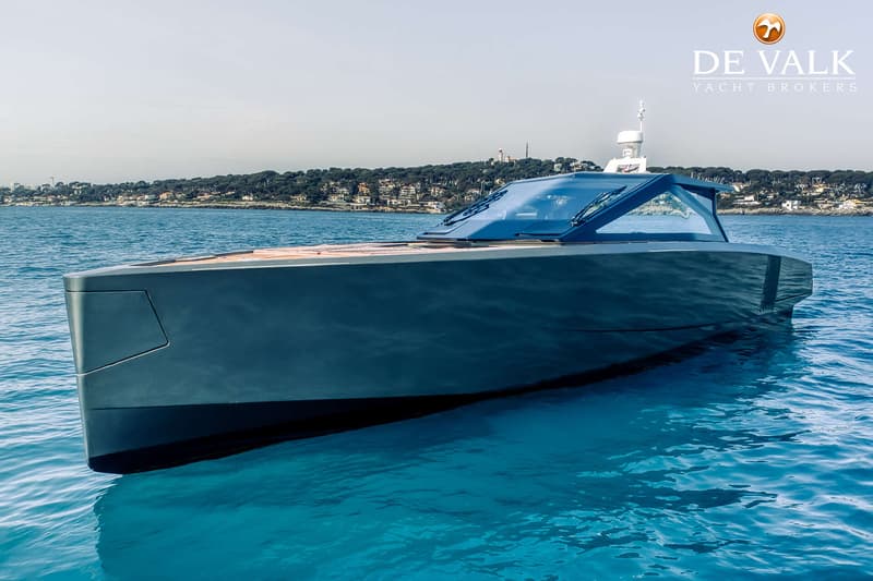 Een donkergrijze motorboot met een houten dek en een glazen opbouw ligt in helderblauw water. — Wally WallyPower58