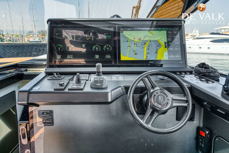 Een stuurstand met twee grote Garmin schermen, een stuurwiel, diverse bedieningsknoppen en een joystick.