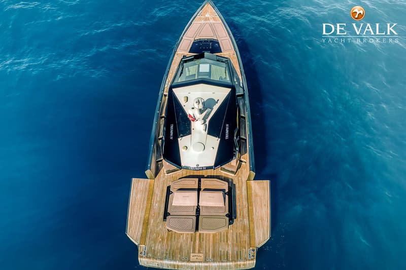 Een luchtfoto toont een luxe jacht met een houten dek en een donkere romp, drijvend op blauw water. — Wally WallyPower58