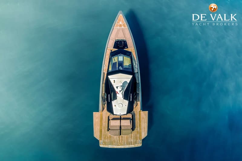Een bovenaanzicht van een motorboot met een houten dek, liggend in helderblauw water. — Wally WallyPower58